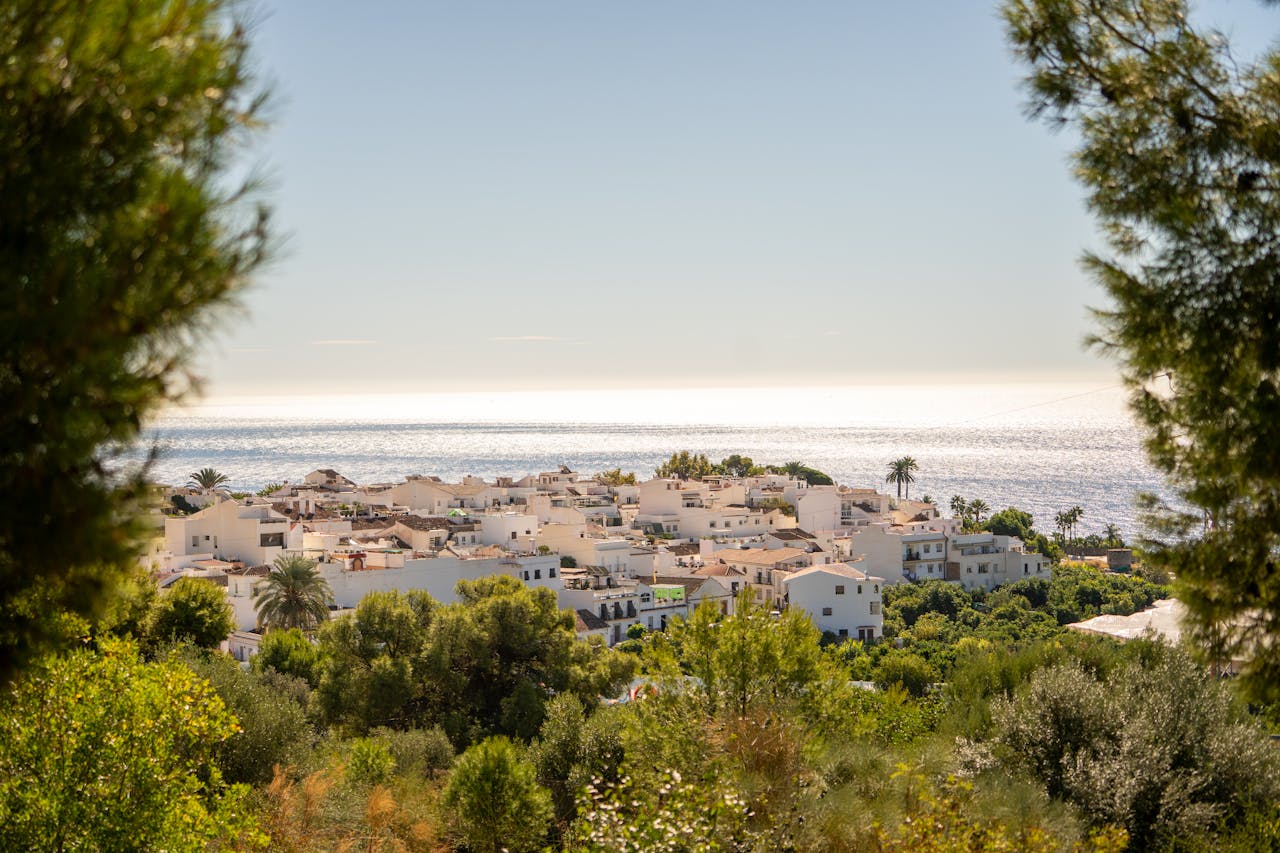 Beautiful coastal view of Nerja, Spain with Mediterranean Sea and whitewashed buildings surrounded by lush greenery.
